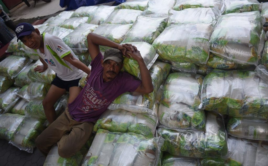 Pekerja berada di atas tumpukan beras dan gula yang dijual saat Operasi Pasar Lumbung Pangan Jawa Timur di Pasar Pucang Anom, Kota Surabaya, Jawa Timur, Minggu (4/12/2022). 