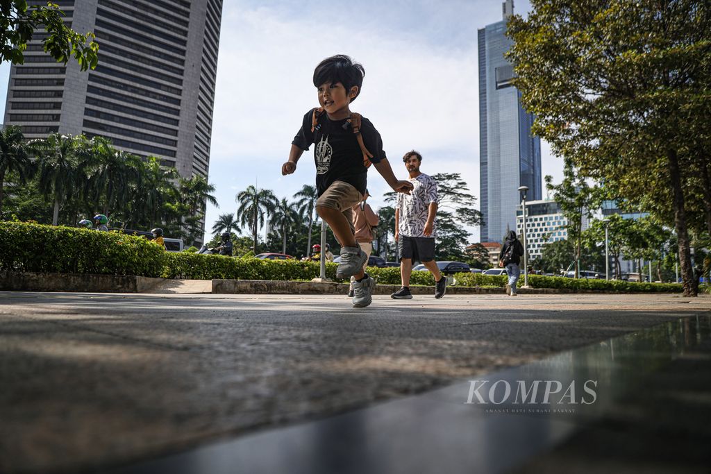 Seorang anak berlarian di atas trotoar di Jalan Jenderal Sudirman, Jakarta, Jumat (1/3/2024). Fasilitas trotoar yang memadai turut mendorong minat warga untuk berjalan kaki dan menggunakan transportasi umum. 