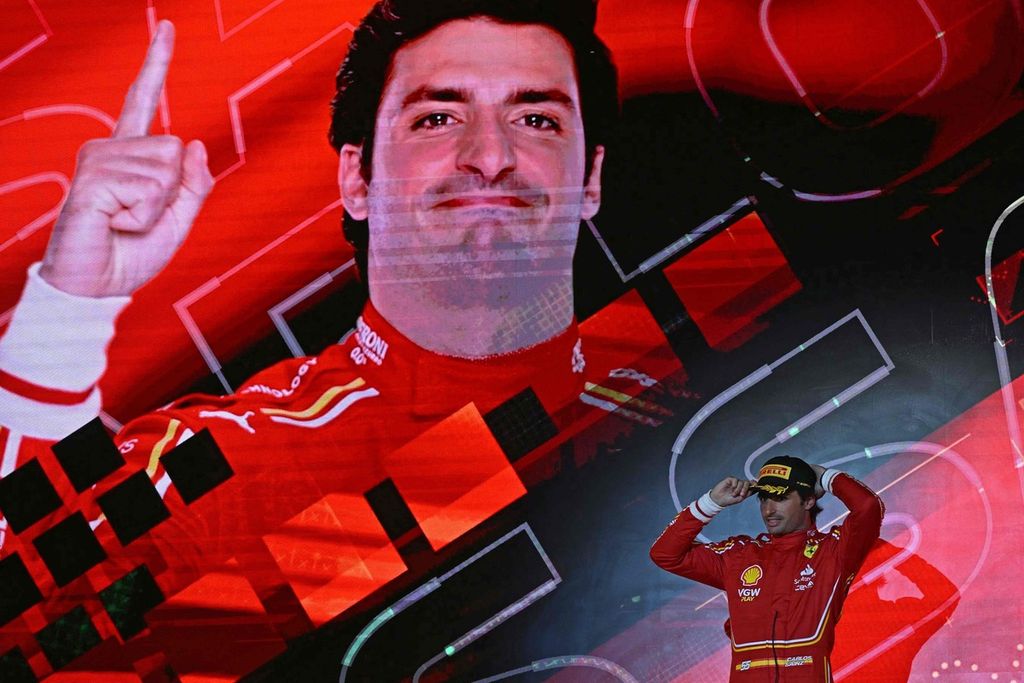 Pebalap Ferrari, Carlos Sainz Jr, berdiri di atas podium ketiga setelah balapan pembuka Grand Prix Formula 1 2024 di Sirkuit Internasional Bahrain, di Sakhir, Sabtu (2/3/2024). 