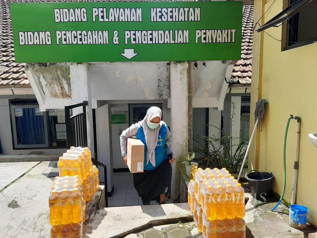 Seorang petugas puskesmas membawa botol-botol minyak goreng ke ambulans, Jumat (8/4/2022). Sebanyak 2.500 liter minyak goreng disiapkan sebagai hadiah bagi warga lansia yang melakukan vaksinasi di 26 puskesmas.