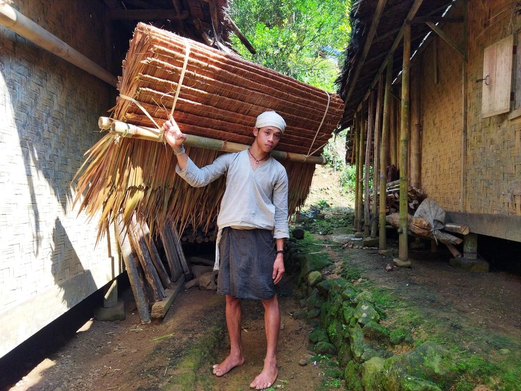 Ata (25), pemuda asal Kampung Cikeusik, Baduy Dalam, berjalan kaki sekitar tiga jam membawa atap seberat sekitar 20 kilogram ke kampung Cibungur, Baduy Luar, untuk dijual, Selasa (19/7/2022).