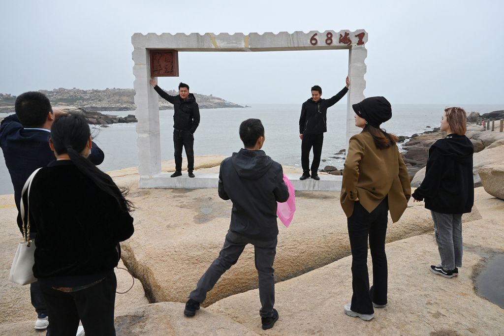 Turis China berpose untuk berfoto di depan Selat Taiwan, di pesisir Pulau Pingtan, titik terdekat dengan Taiwan, di Provinsi Fujian, sebelah tenggara China, pada 6 April 2023.