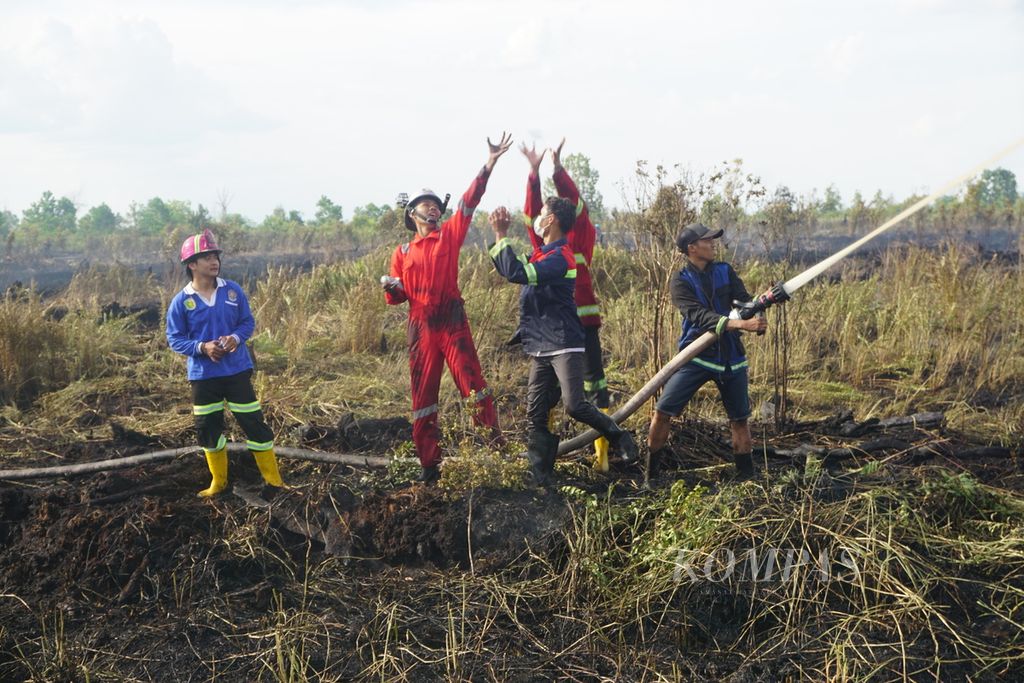 Petugas gabungan dari BPBD Kota Palangkaraya dan Manggala Agni serta sukarelawan pemadam kebakaran berebut botol air minum di sela-sela pemadaman lahan yang terbakar di Jalan Danau Rangas, Kota Palangkaraya, Kalimantan Tengah, awal Oktober 2020.