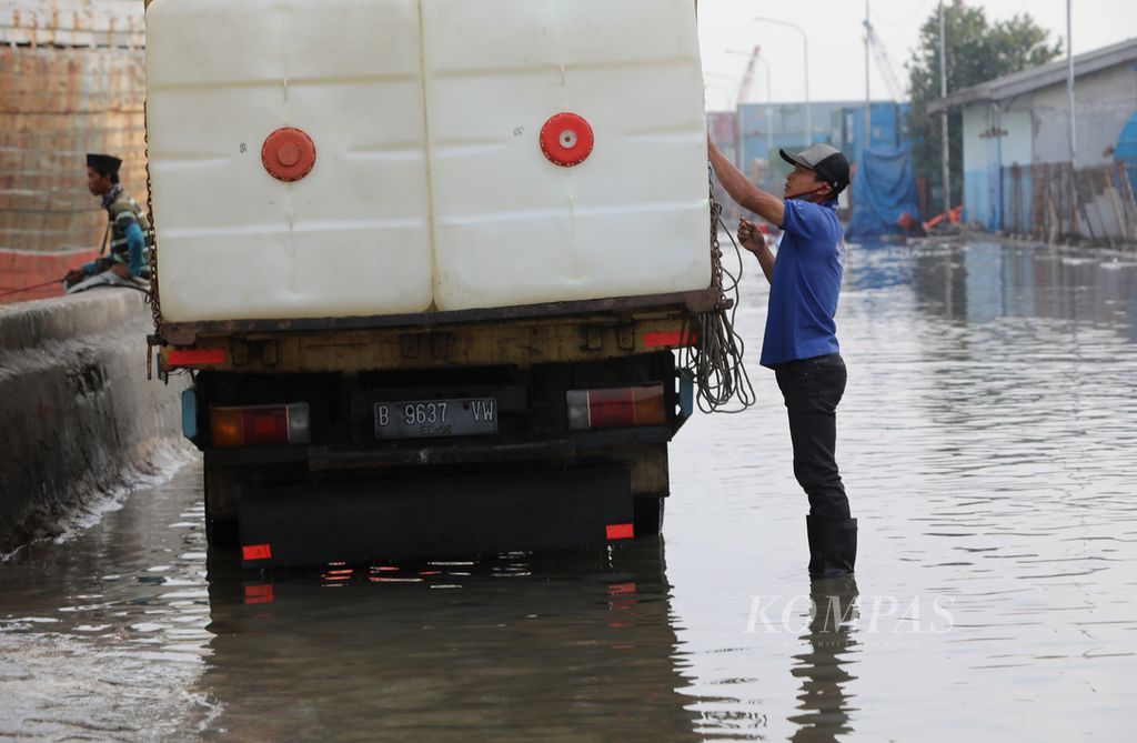 Pekerja bersiap memulai proses muat barang ke kapal di Pelabuhan Sunda Kelapa, Pademangan, Jakarta Utara, yang tergenang banjir rob, Jumat (5/6/2020).
