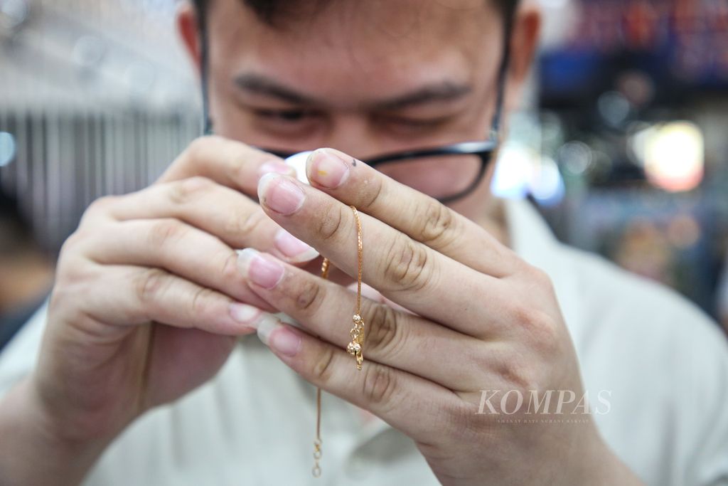 Pedagang memeriksa perhiasan emas yang hendak dijual oleh pengunjung di toko emas Bintang Timur, Kebayoran Lama, Jakarta Selatan, Sabtu (8/7/2023). 