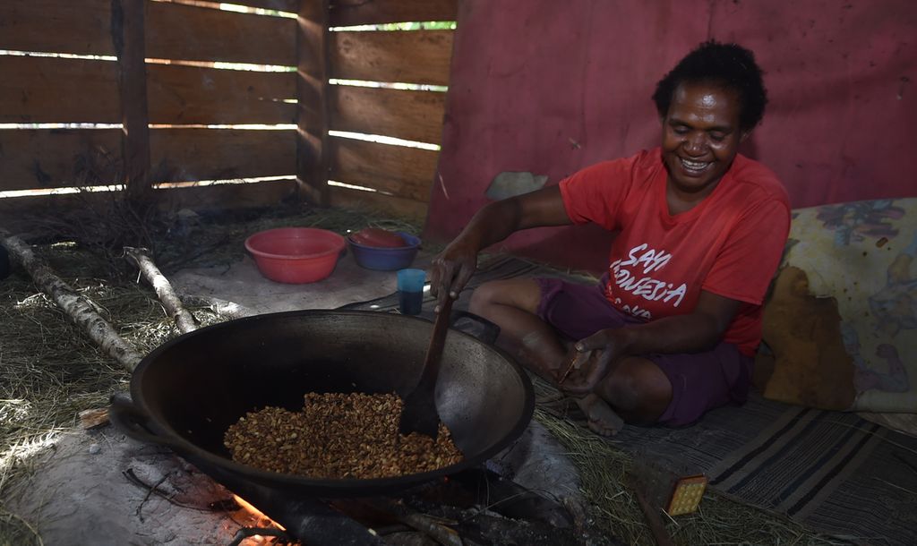 A villager roasts coffee beans on Wednesday (17/11/2021) in Kugima village of Wolo district, Jayawijaya, Papua.