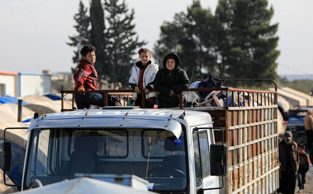Anak-anak pengungsi Suriah menumpang di atas truk di kamp sebelum pindah menuju kompleks perumahan baru mereka di daerah yang dikuasai oposisi Bizaah, timur kota al-Bab di Provinsi Aleppo utara yang dibangun dengan dukungan badan darurat Turki AFAD setelah meninggalkan kamp terdekat, Rabu (9/2/2022). 