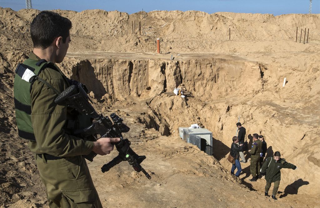 Foto yang diambil pada 18 Januari 2018 memperlihatkan seorang anggota militer Israel mengawasi rombongan yang tengah melihat pintu masuk sebuah terowongan, yang diyakini digunakan kelompok Hamas, yang terletak di Kissufim, Israel selatan. 
