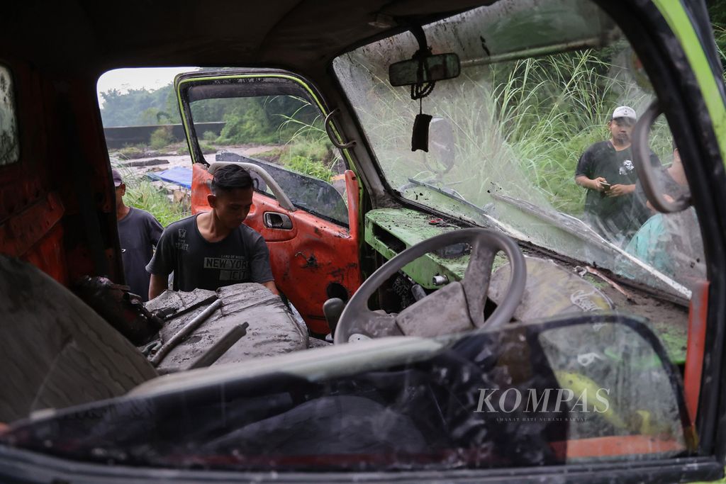 Warga melihat kabin truk yang terjebak aliran banjir lahar hujan dari Gunung Merapi di Sungai Boyong, Kabupaten Sleman, Daerah Istimewa Yogyakarta, Kamis (3/2/2022). 