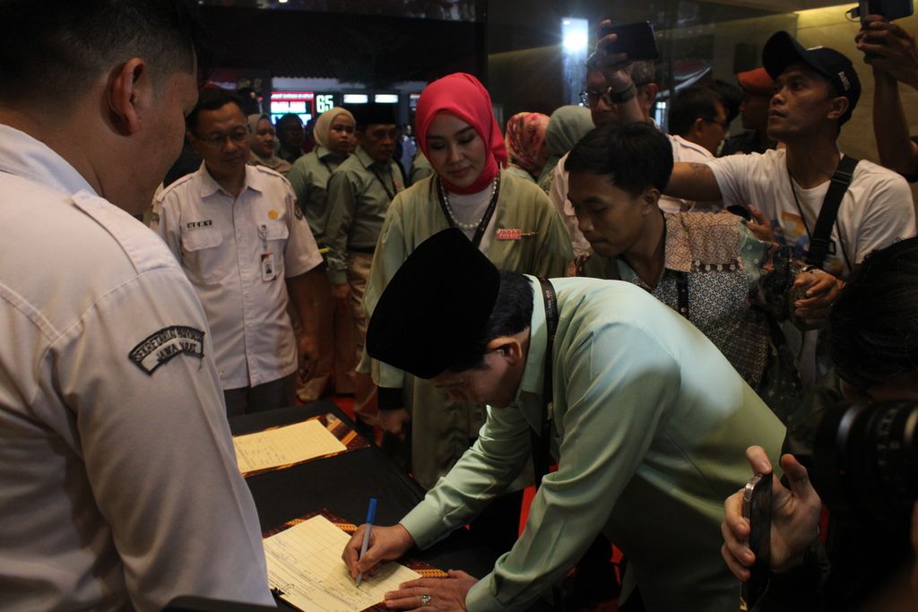 Calon gubernur Jawa Barat, Acep Adang Ruhiat, menandatangani daftar hadir didampingi wakilnya, Gita Dwi Natarina, di kantor Komisi Pemilihan Umum Jabar, Kota Bandung, Senin (23/9/2024) malam. 