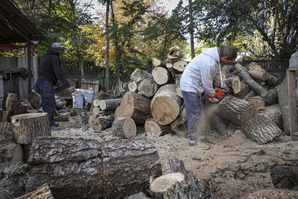 Dua pria tengah memotong kayu untuk stok penghangat musim dingin di Chisinau, Moldova, Sabtu (15/10/2022). Eropa memasuki musim dingin saat pasokan energi di negara itu mengalami krisis. (AP Photo/Aurel Obreja)