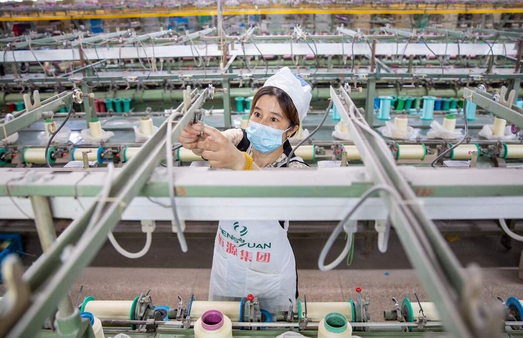Seorang karyawan bekerja di pabrik tekstil di Nantong, Provinsi Jiangsu, China timur, yang memproduksi kain sutra untuk diekspor, 15 Juni 2022.  