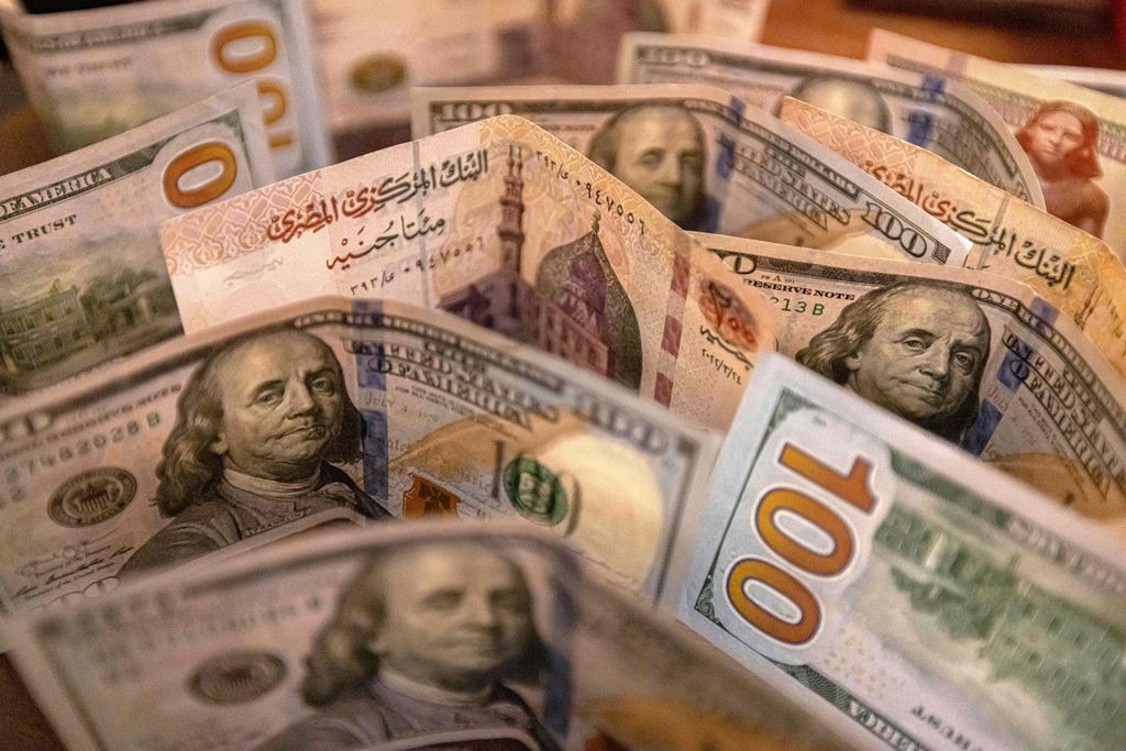 Foto yang diambil pada 25 Agustus 2022 ini memperlihatkan mata uang pound Mesir dan dollar AS. Kenaikan suku bunga dollar AS akan memberi tekanan terhadap mata uang negara-negara berkembang. 