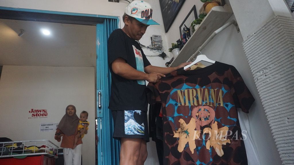 Ginanjar Wahyu Saputro menata koleksi kaus band yang diperolehnya dari <i>thrifting</i> atau berburu pakaian bekas di Jaws Store, Kota Surakarta, Jawa Tengah, Rabu (8/6/2022). 