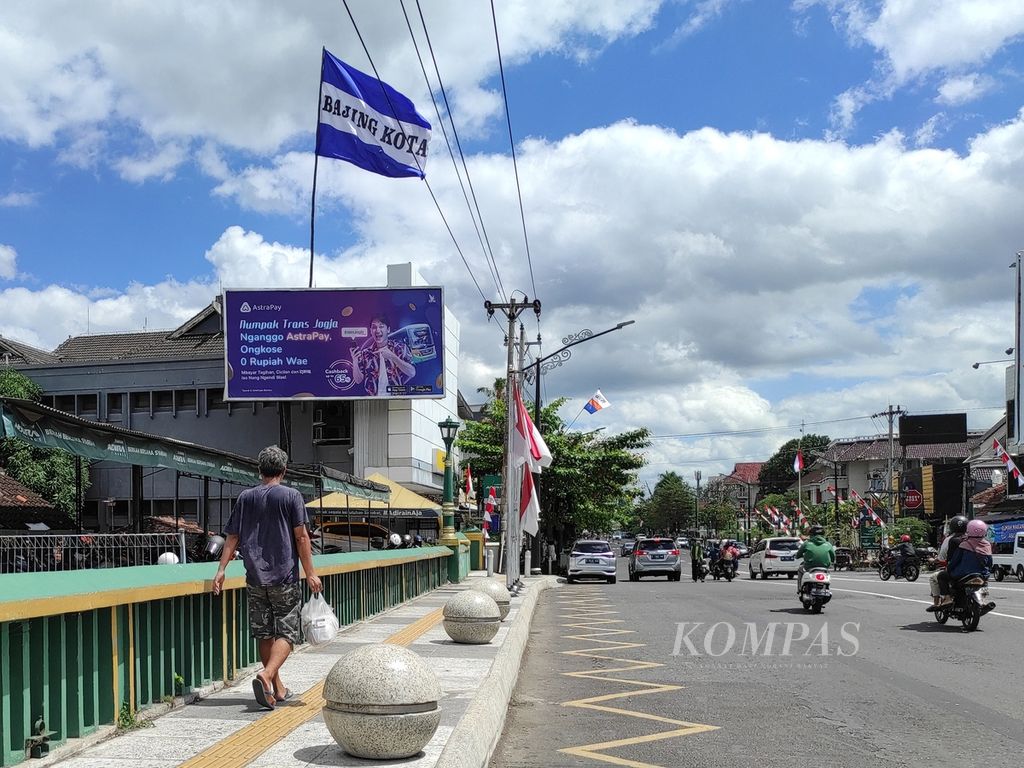 Seorang warga melintasi jembatan yang terdapat bendera <i>fans </i>PSIM Yogyakarta di Jalan Jenderal Sudirman, Kotabaru, Kota Yogyakarta, Daerah Istimewa Yogyakarta, Senin (9/8/2022). Meski kampanye #BIRUKANDIY telah berjalan sejak 2019, pendukung klub itu tetap konsisten memasang bendera baru setiap tahun.
