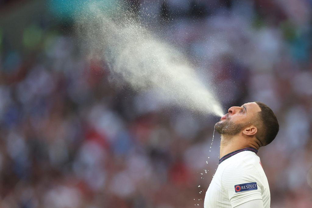 Pemain bertahan Inggris, Kyle Walker menyemprotkan air dari mulutnya di sela-sela pertandingan melawan Denmark di semifinal Euro 2020, 8 Juli 2021. Inggris menang 2-1 atas Denmark.