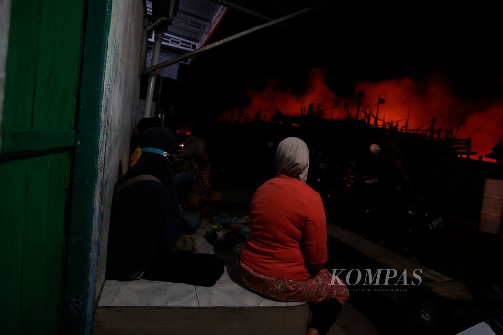 Warga berjaga di depan rumah saat terjadi kebakaran hebat yang melanda puluhan kapal di Pelabuhan Perikanan Pantai Tegalsari, Kota Tegal, Jawa Tengah, Selasa (15/8/2023).
