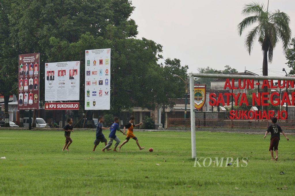 Anak-anak bermain sepak bola di Alun-alun Satya Negara, Sukoharjo, Jawa Tengah, yang dipasangi baliho kampanye oleh KPU Sukoharjo, Selasa (9/1/2024). Berlangsungnya masa kampanye pemilu menjadi sarana belajar tentang pesta demokrasi bagi semua kalangan, termasuk anak-anak.