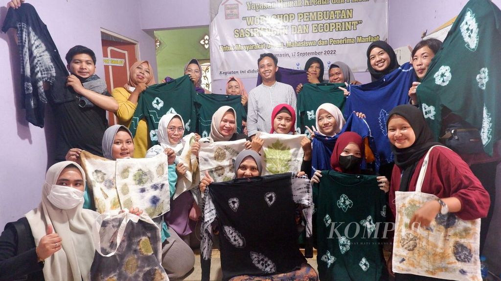 Warga dan mahasiswa memperlihatkan kaus sasirangan dan tas kain <i>ecoprint </i>yang sudah jadi dalam kegiatan lokakarya pembuatan sasirangan dan <i>ecoprint </i>di Rumah Kreatif dan Pintar, Banjarmasin Selatan, Kota Banjarmasin, Kalimantan Selatan, Sabtu (17/9/2022).