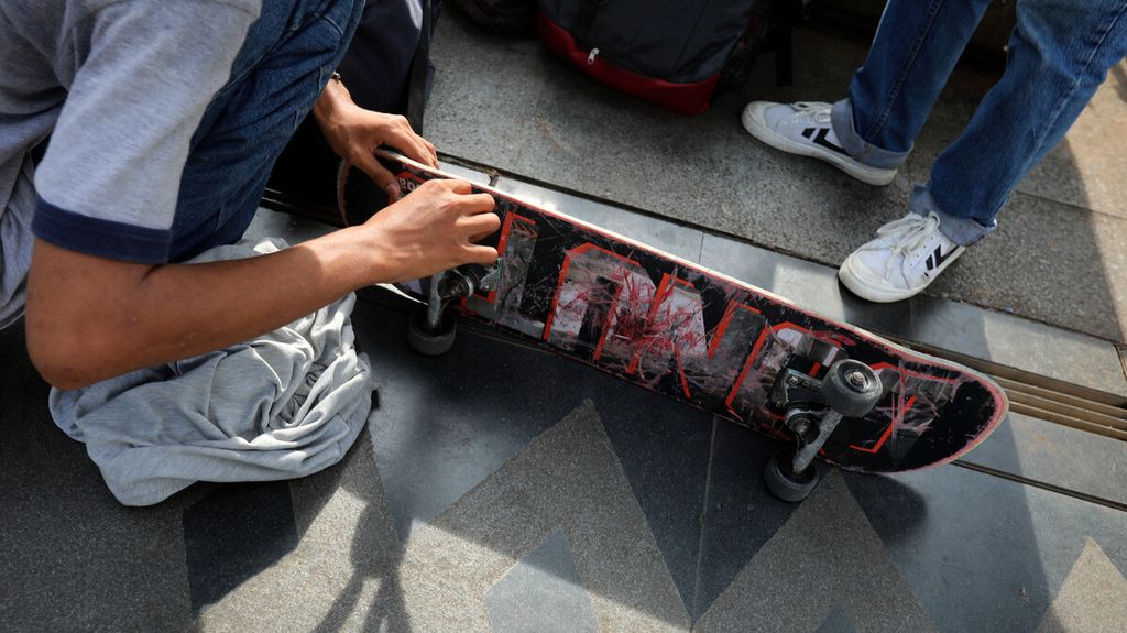 Pemain <i>skateboard </i>memperbaiki roda di sela-sela waktu bermain di trotoar Jalan Jenderal Sudirman-Thamrin, Jakarta, Jumat (12/3/2021).