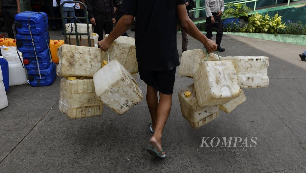 Pekerja membawa jeriken kosong yang akan diisi minyak goreng curah dalam pendistribusian khusus untuk pedagang di Pasar Anyar, Kota Tangerang, Banten, Selasa (29/3/2022). 
