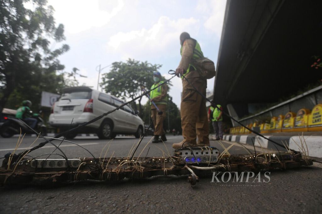 Komunitas saber ranjau paku bersama Satlantas Jakarta Barat, dengan menggunakan magnet, membersihkan Jalan Letjen S Parman, Tomang, Jakarta, dari ranjau paku yang sengaja disebar oleh oknum tidak bertanggung jawab, Minggu (9/3/2021). 