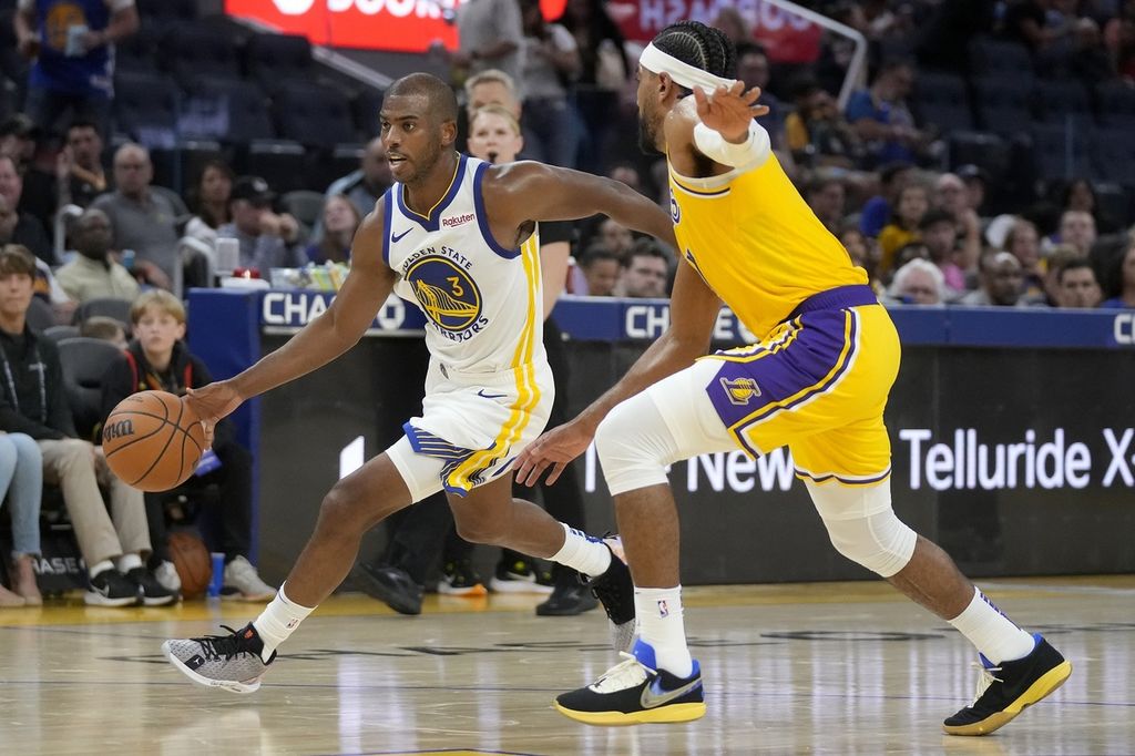 Pemain Golden State Warriors, <i>guard </i>Chris Paul (kiri), mendribel bola dengan dihadang pemain Los Angeles Lakers, Gabe Vincent, pada laga NBA di Chase Center, San Francisco, Minggu (8/10/2023).