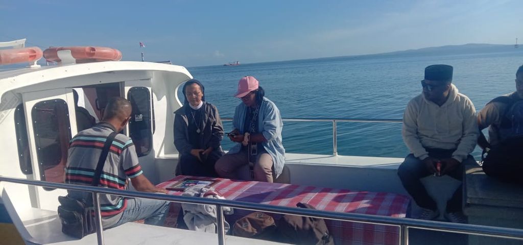Benedikta Antonela Dasilva (bertopi) sedang berada dalam kapal motor milik rakyat untuk mengantar jenazah Agnes Peni Muda ke Pulau Solor, Flores Timur.