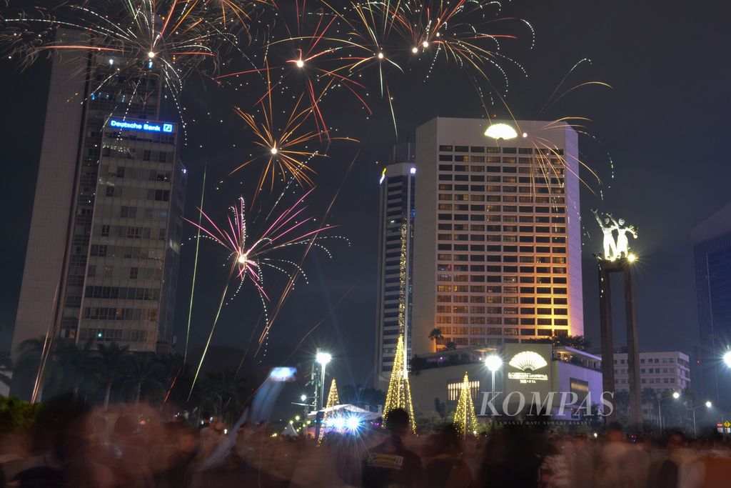 Warga menyaksikan pertunjukan kembang api di sekitaran Bundaran Hotel Indonesia (HI), Jakarta Pusat, Minggu (1/1/2023). Bundaran HI menjadi salah satu kawasan yang dipilih warga untuk merayakan pergantian tahun. 