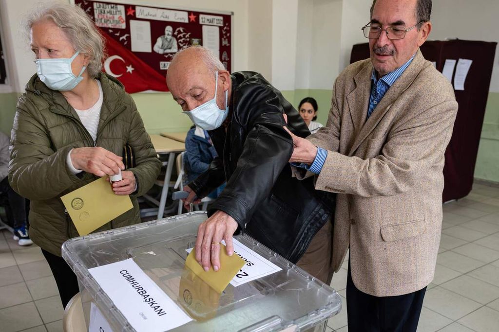 Seorang warga lansia dibantu untuk memasukkan kertas suara ke dalam kotak suara saat pilpres Turki putaran kedua, Minggu (28/5/2023) di sebuah tempat pemungutan suara di Izmit, Turki.