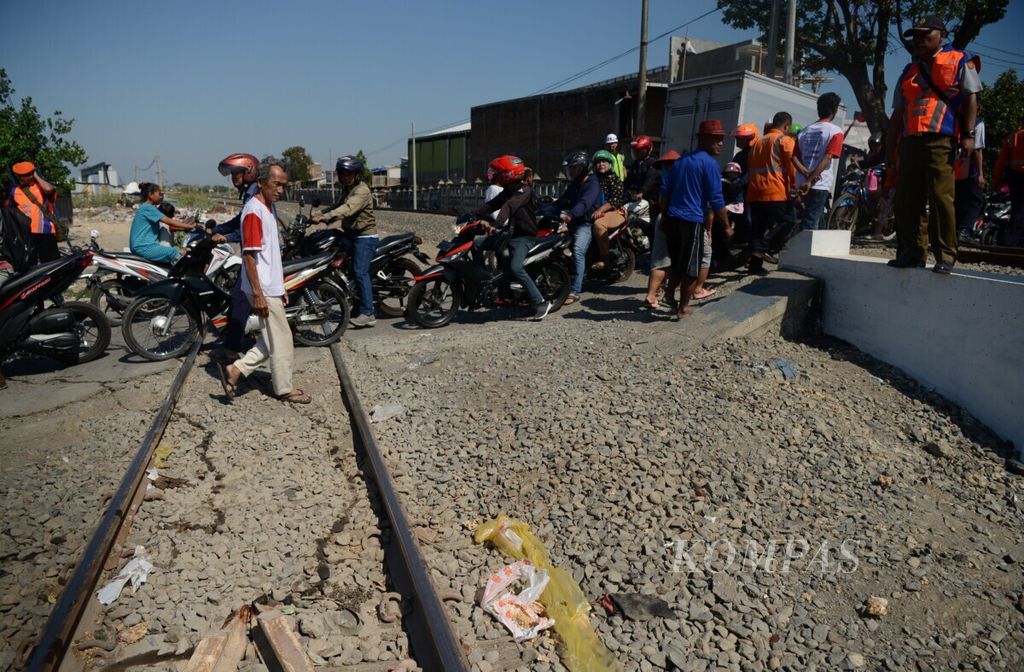 Warga melewati pelintasan rel kereta api tanpa palang pintu di Kampung Cilosari, Kota Semarang, Jawa Tengah, Rabu (21/8/2019).