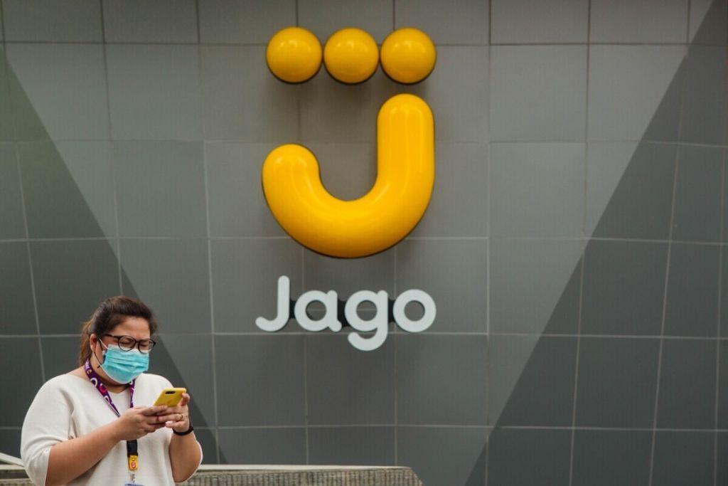 Warga sedang berjalan melewati logo Bank Jago.