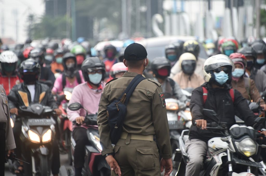 Petugas satpol PP mengawasi kendaraan roda dua yang masuk ke Surabaya saat berlangsung sosialiasi oleh petugas gabungan pada hari pertama pemberlakuan pembatasan kegiatan masyarakat (PPKM) di Bundaran Waru, Surabaya, Jawa Timur, Senin (11/1/2021). 