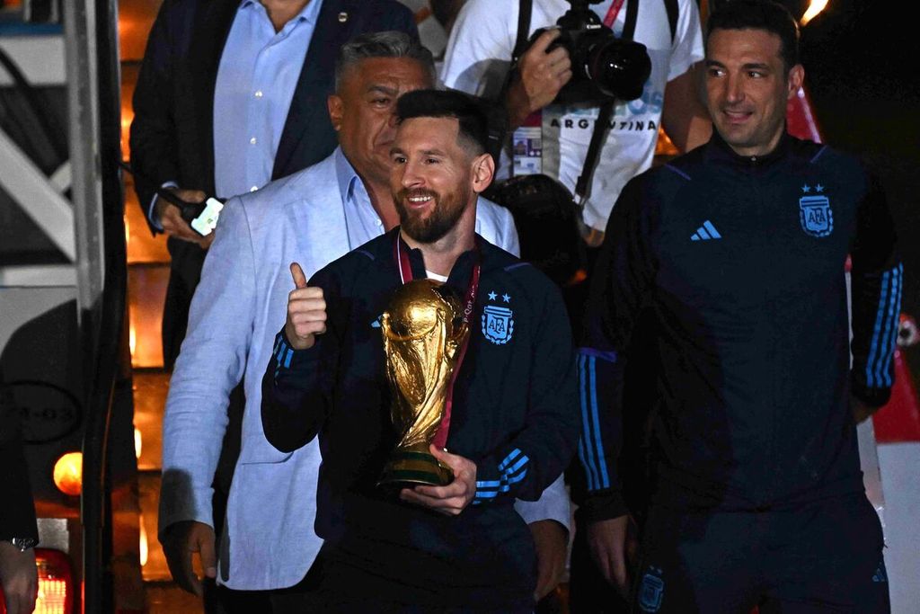 Kapten Argentina Lionel Messi membawa trofi Piala Dunia saat tiba di Bandara Internasional Ezeiza, Selasa (20/12/2022). Dia datang bersama seluruh anggota tim.
