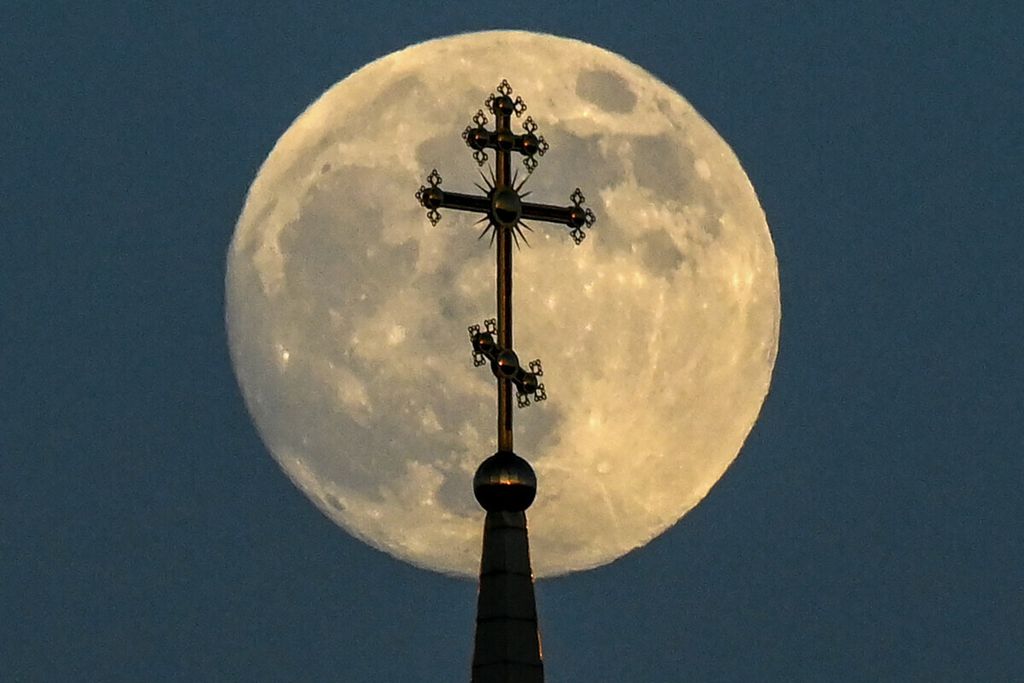 Bulan purnama di balik salib di atas sebuah gereja Ortodoks di kota Rossosh, wilayah Voronezh, pada akhir 25 Mei 2021. 