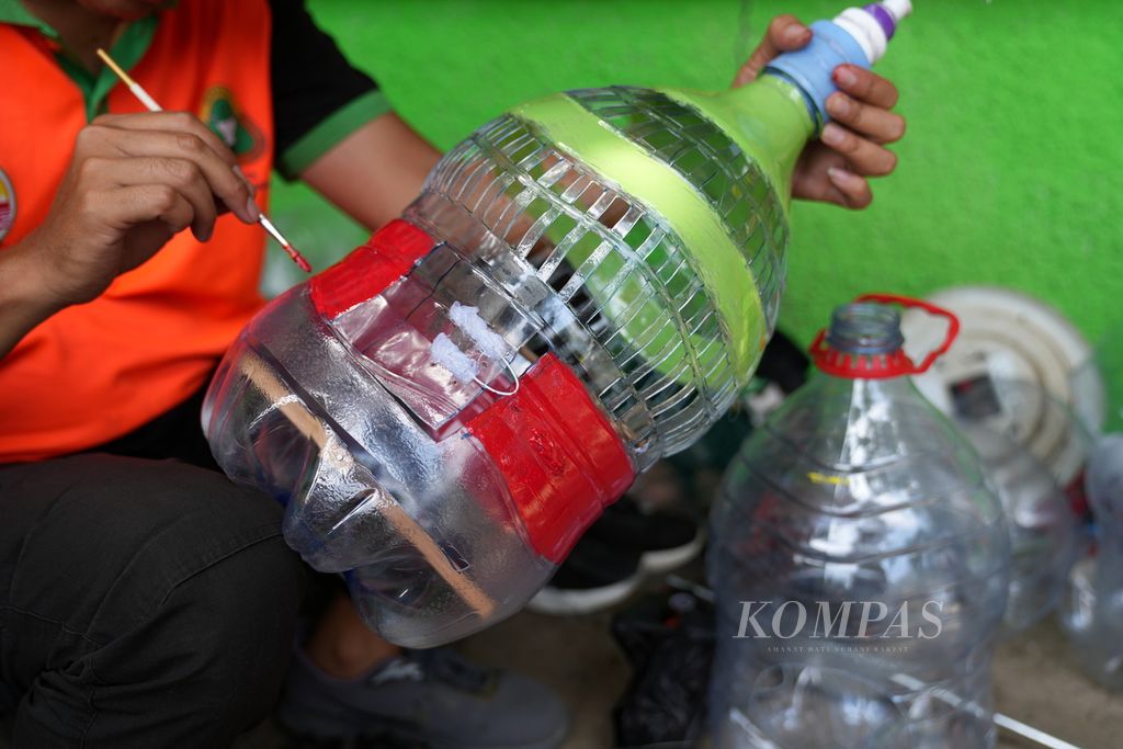 Petugas Unit Penanganan Sampah (UPS) Badan Air Dinas Lingkungan Hidup mengecat limbah galon plastik menjadi kurungan burung di Waduk Elok, Cakung, Jakarta Timur, Rabu (15/5/2024). Dalam seminggu terakhir, tim UPS Badan Air Kecamatan Cakung mengolah limbah galon plastik sekali pakai menjadi barang lebih berharga, di antaranya pot, lampu kamar, kurungan burung, dan akuarium. 