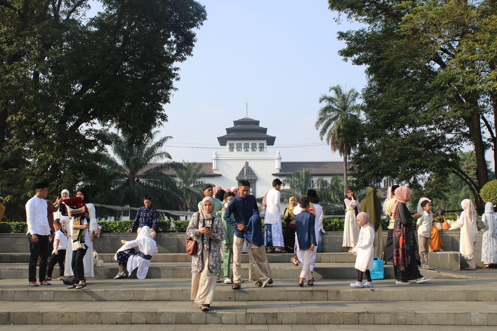 Warga berfoto dan bercengkerama dengan latar berlakang Gedung Sate di Lapangan Gasibu, Kota Bandung, Jawa Barat, Rabu (10/4/2024). 