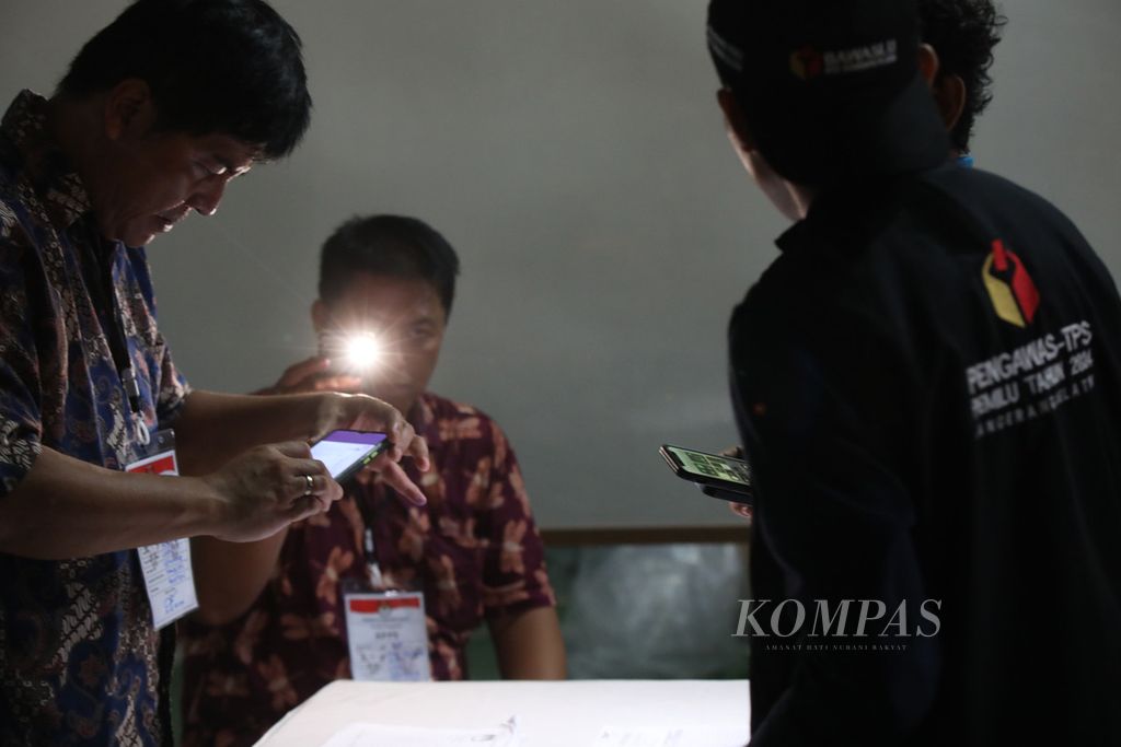 Dibantu penerangan telepon genggam petugas KPPS melakukan perekaman dokumen pemilu untuk diunggah ke aplikasi Sirekap di TPS 27 Kelurahan Lengkong Gudang Timur, Serpong, Tangerang Selatan, Banten, Rabu (14/2/2024) malam. 