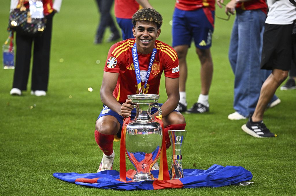 Penyerang Spanyol, Lamine Yamal, berpose dengan trofi juara Piala Eropa 2024 di Berlin, Senin (15/7/2024) dini hari WIB. Yamal adalah salah satu kunci keberhasilan &quot;La Roja&quot; merebut trofi Euro.