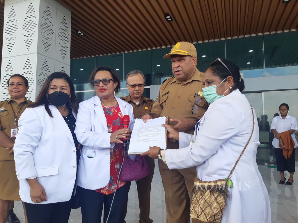 Yunike Howay selaku perwakilan dari para dokter yang berunjuk rasa menyerahkan surat pernyataan sikap kepada Staf Ahli Gubernur Papua Gerzon Jitmau di halaman Kantor Gubernur Papua, Senin (28/8/2023). 