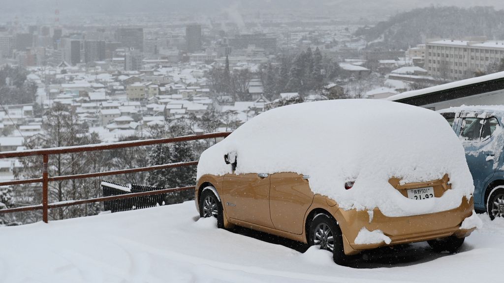 Sebuah mobil berselimut salju saat diparkir menghadap ke kota Nagano, Jepang, 25 Januari 2023. 