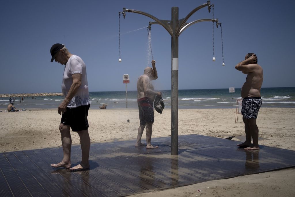 Sejumlah pria mandi di pancuran umum tepi pantai di Tel Aviv, Israel, Kamis (13/7/2023). Badan Meteorologi Israel telah mengeluarkan peringatan cuaca panas kepada warganya yang berpotensi meningkatkan risiko dehidrasi dan serangan suhu panas ekstrem. Mitigasi bencana suhu panas terus meningkat dengan sistem peringatan dini yang telah dilakukan pemerintah di sejumlah negara.