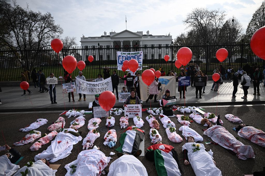Aktivis berbaring di antara instalasi seni yang melambangkan korban warga sipil Palestina, termasuk anak-anak dan bayi, saat berdemo di depan Gedung Putih, Washington, Amerika Serikat, Sabtu (2/12/2023). 