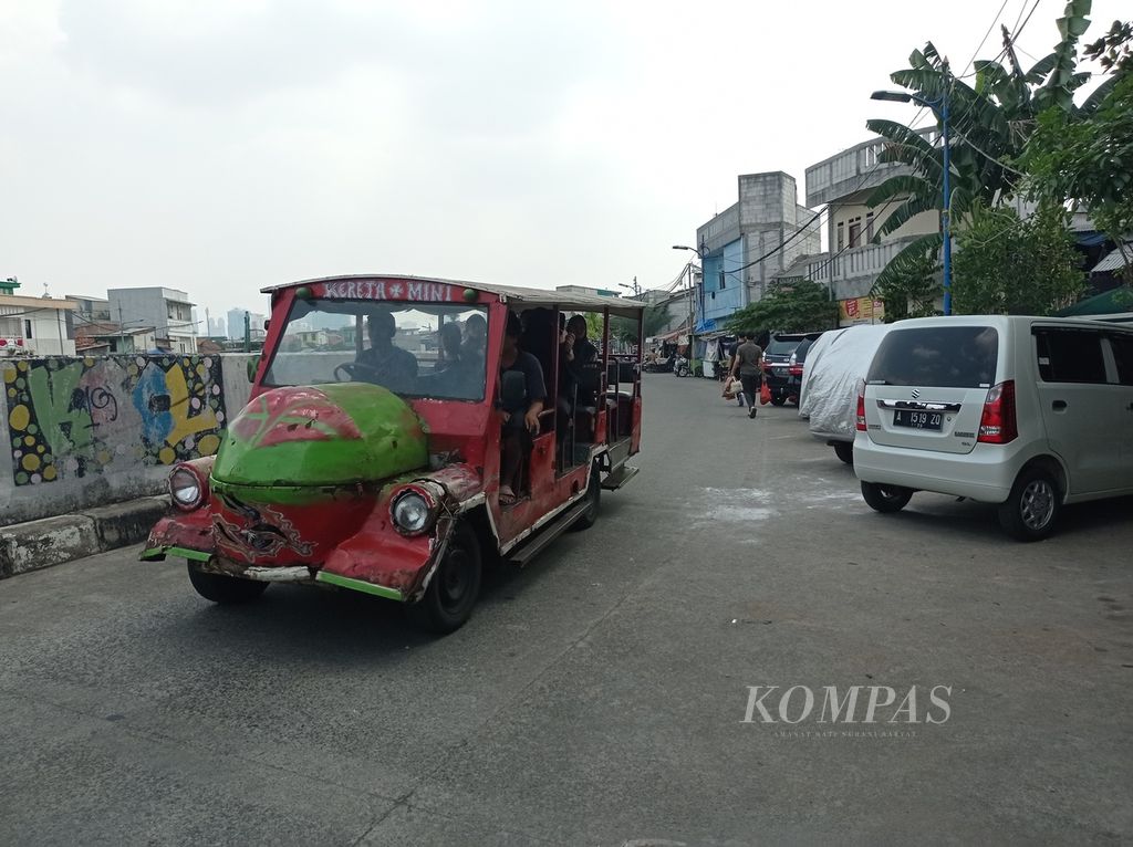 Odong-odong melintas di Jalan Inspeksi Kali Ciliwung, Kampung Pulo, Kecamatan Jatinegara, Jakarta Timur, Minggu (31/7/2022).