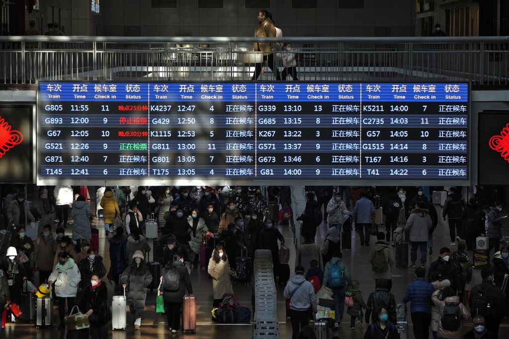 Pelancong berjalan melalui papan keberangkatan kereta di Stasiun Kereta Api Barat di Beijing, Minggu (15/1/2023). Organisasi Kesehatan Dunia mengimbau China untuk terus merilis informasi tentang kasus Covid-19 setelah pemerintah mengumumkan hampir 60.000 orang tewas sejak awal Desember. 