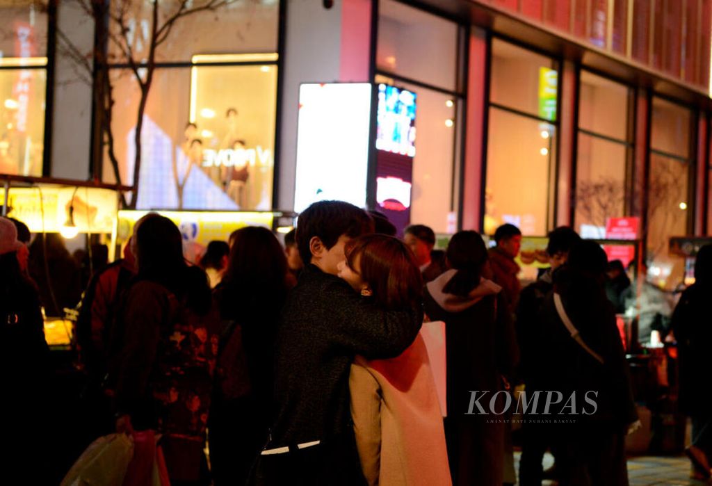Sepasang kekasih berpelukan di tengah keramaian kawasan Myeongdong yang juga merupakan surga belanja bagi wisatawan di Korea Selatan, Senin (23/3/2020).