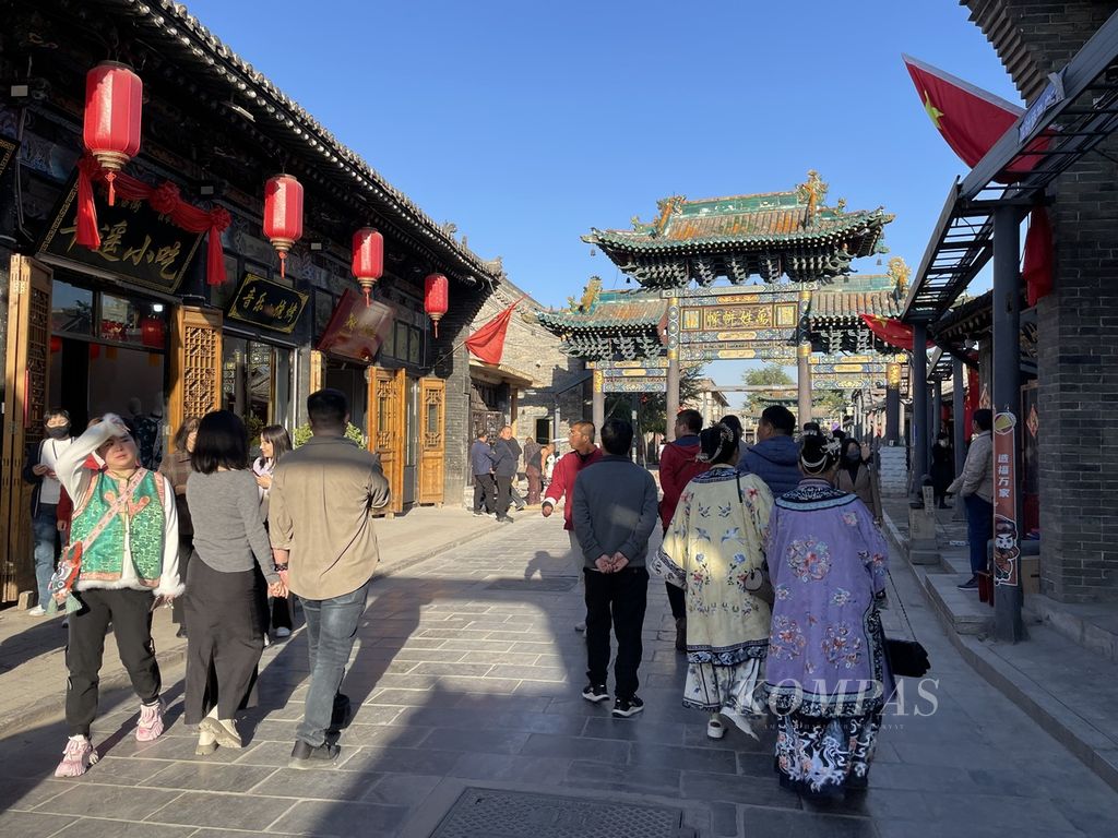 Banyak pengunjung yang jalan-jalan keliling kota kuno Pingyao di Provinsi Shanxi, China, dengan mengenakan pakaian tradisional yang bisa disewa seharian. Di dalam Pingyao banyak tempat penyewaan pakaian tradisional lengkap dengan jasa rias wajah dan rambut. Foto diambil pada 20 Oktober 2023.