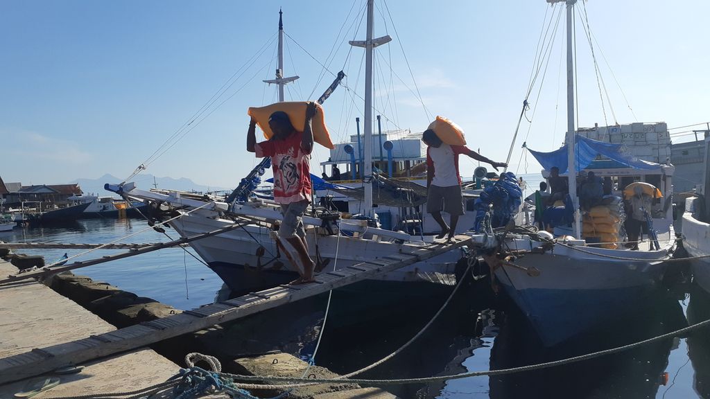 Buruh panggul mengeluarkan beras dari dalam kapal di Pelabuhan Rakyat Wuring, Maumere, Kabupaten Sikka, Nusa Tenggara Timur, pada Kamis (16/12/2021).  