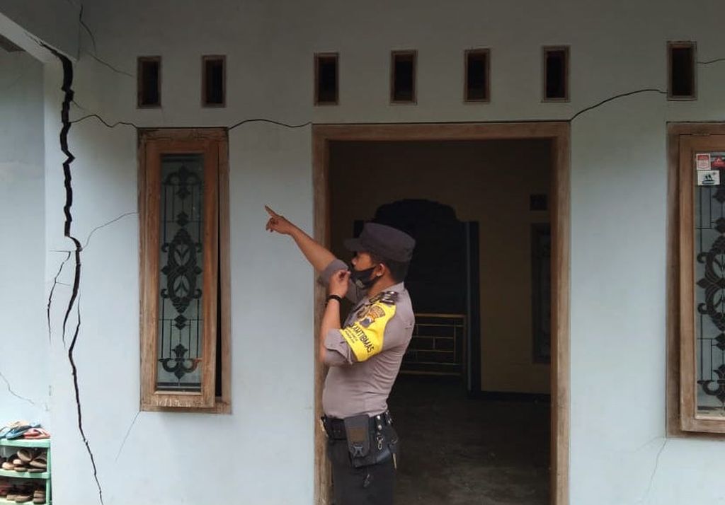Polisi menunjukkan rumah warga yang dindingnya retak akibat bencana tanah bergerak di Desa Dermasuci, Kecamatan Pangkah, Kabupaten Tegal, Jawa Tengah Minggu (13/2/2022). Akibat kejadian itu, ratusan rumah rusak ringan hingga berat dan ratusan warga mengungsi.