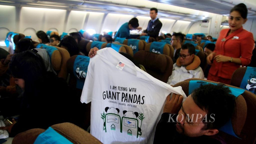 Pramugari Garuda Indonesia membagikan kaus bergambar sepasang panda raksasa dari China untuk Indonesia dalam penerbangan dari Chengdu, Provinsi Sichuan, menuju Jakarta, Kamis (28/9/2017) pagi. 